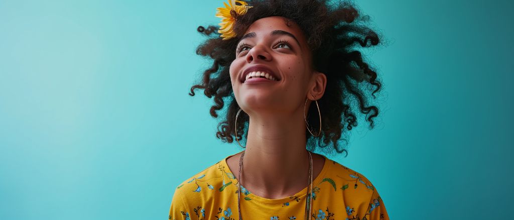 Joyful woman with curly hair and a yellow floral dress against a blue background
