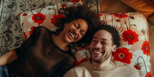 A cheerful couple lying down together on a floral patterned bed