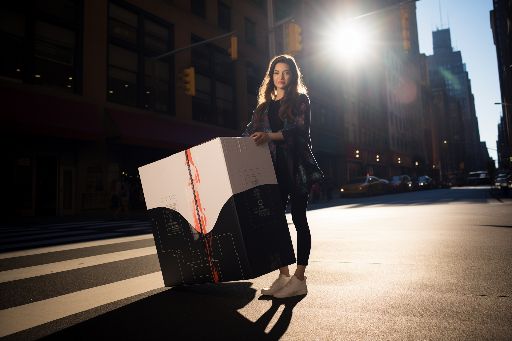 Confident woman with gift box in vibrant city setting