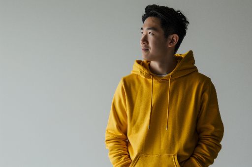 Young man in yellow hoodie looking away thoughtfully