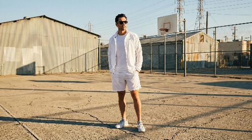 Man in white outfit stands on an outdoor basketball court.