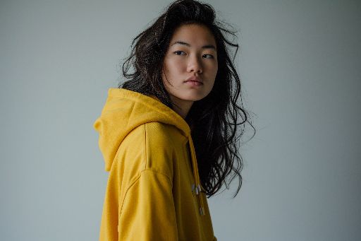 Young woman in a yellow hoodie looking over her shoulder