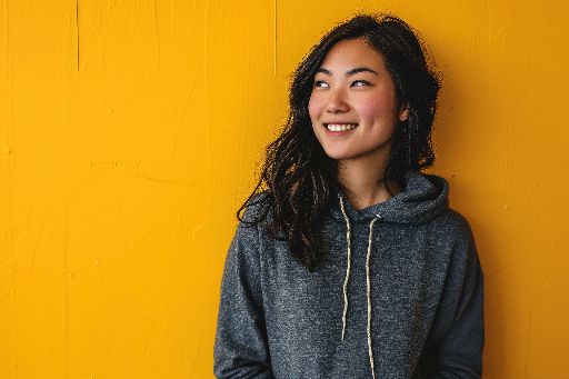 Smiling young woman in hoodie against yellow background