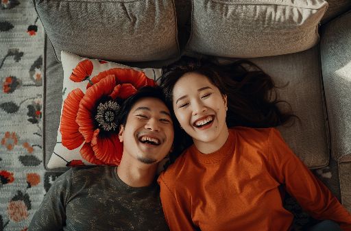Joyful couple lying on the floor with a red flower, sharing a laugh