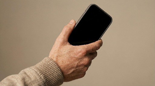 Person holding a smartphone against a neutral background.