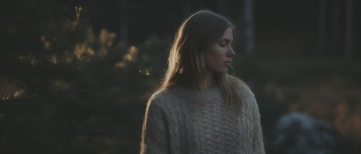 Woman in sweater at dusk with forest background