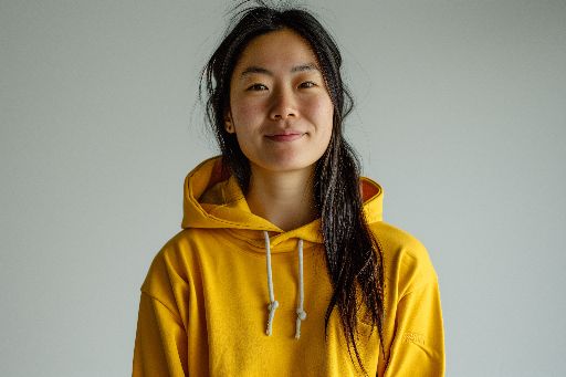 Young woman in yellow hoodie with a subtle smile